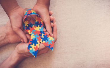 Hands holding puzzle ribbon for autism awareness