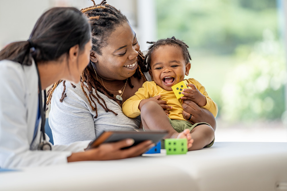 two women holding baby playing with blocks
