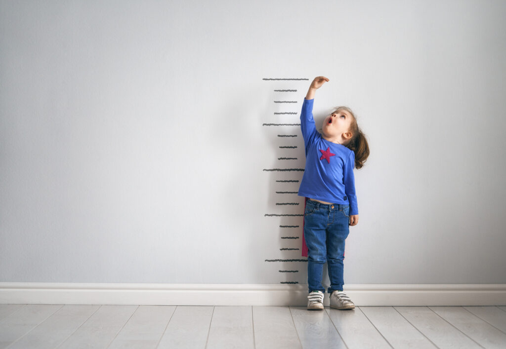 toddler measuring herself against the wall